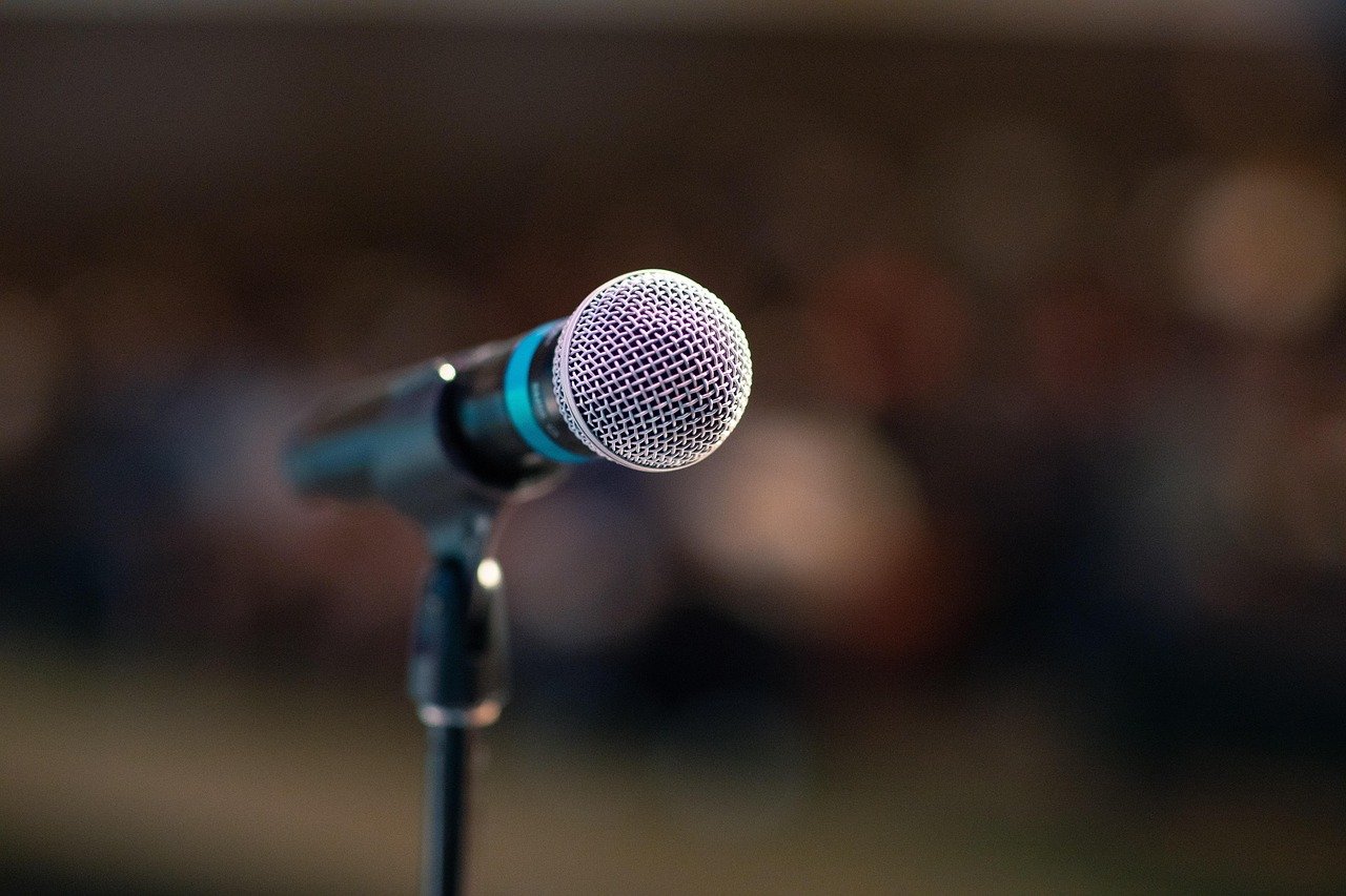 A microphone on a stand in front of a softly blurred audience