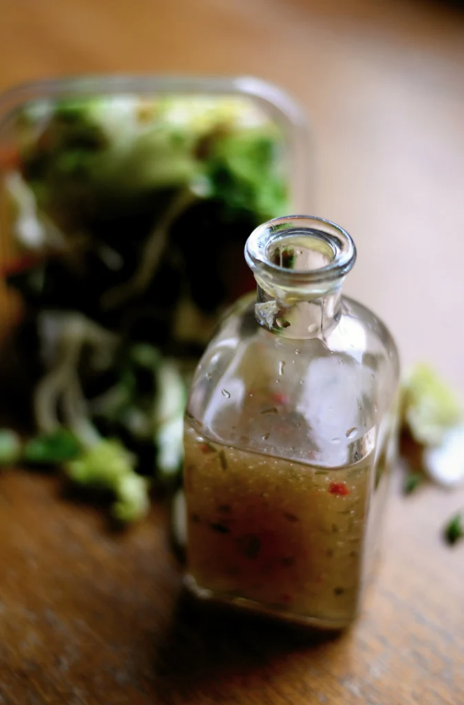 Glass bottles of golden sesame and herbal oil arranged on a wooden surface for Ayurvedic practice