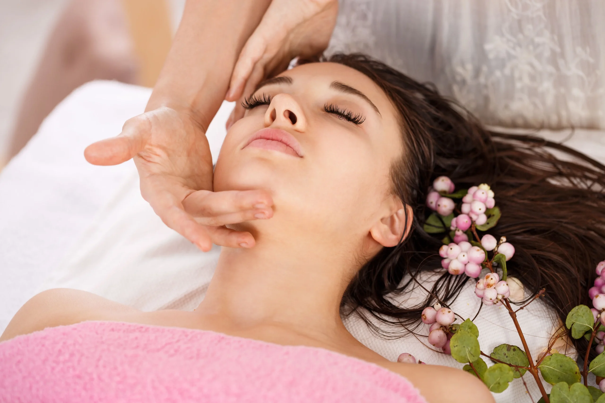 Woman performing Ayurvedic self-massage with warm sesame oil in a calm, candlelit bedroom setting