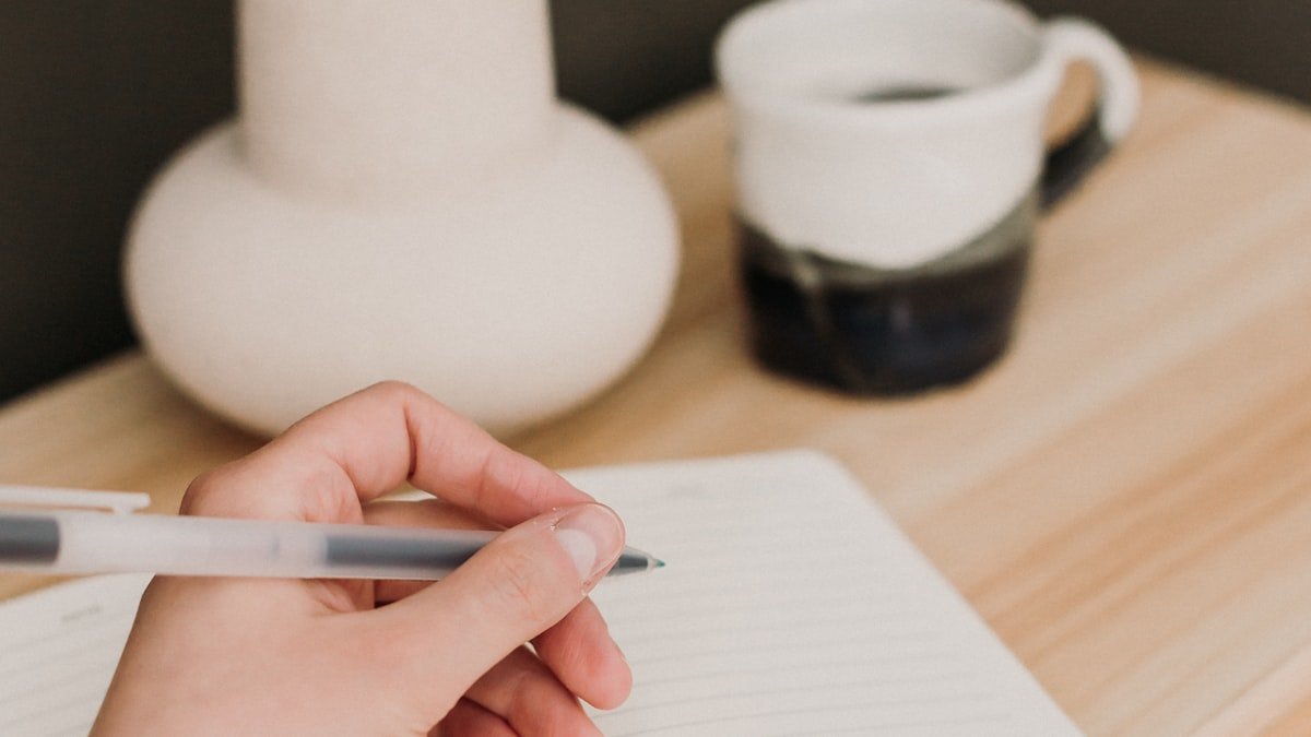 A person writing in a journal with a pen, applying a quote to their own life