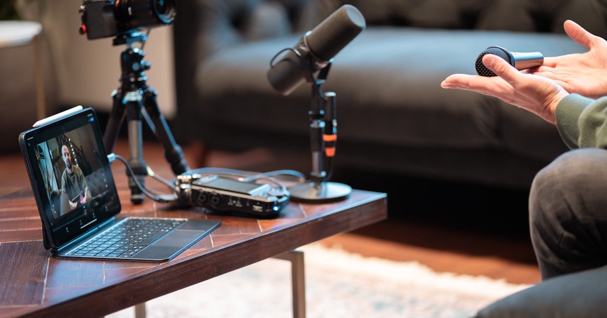 A podcast recording setup with microphone, camera, and laptop