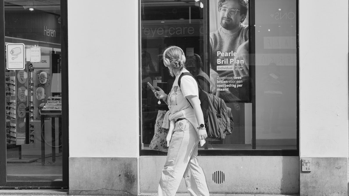 A woman wearing headphones while walking outside, listening to a podcast