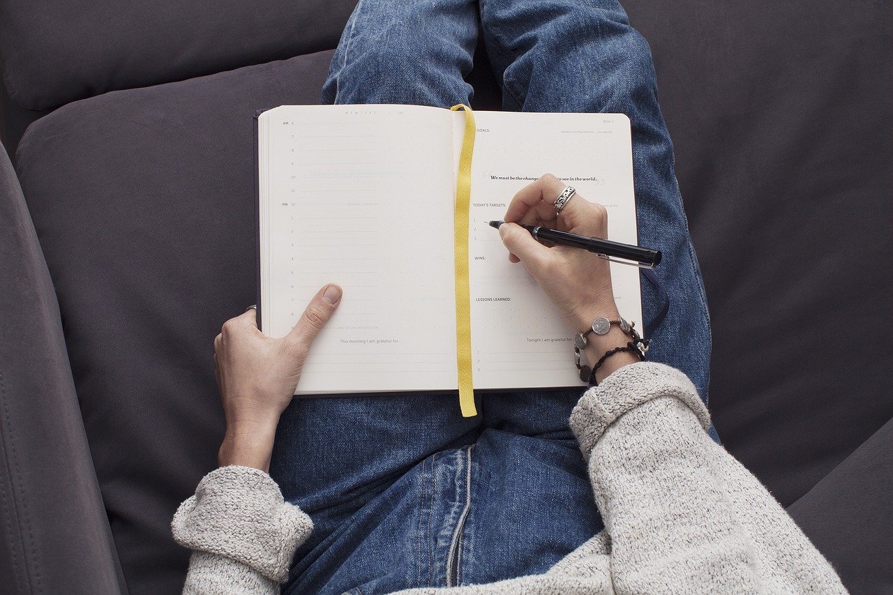 A blank journal notepad with a pen resting on top, ready for a new entry.