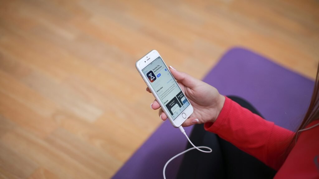 A person sitting on a yoga mat browsing a meditation app in the App Store on their phone.
