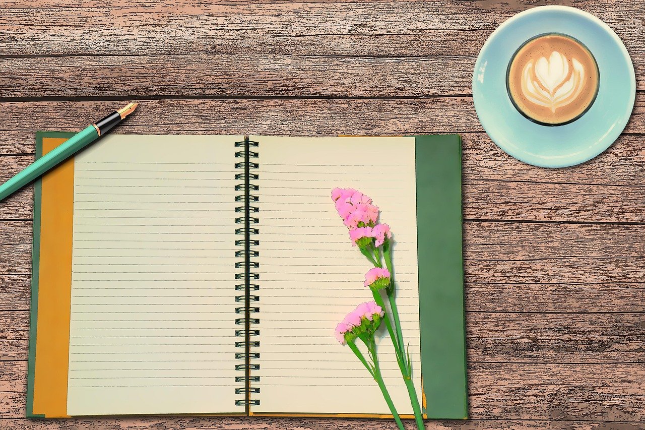 An open journal notebook filled with handwritten pages, resting on a wooden surface.