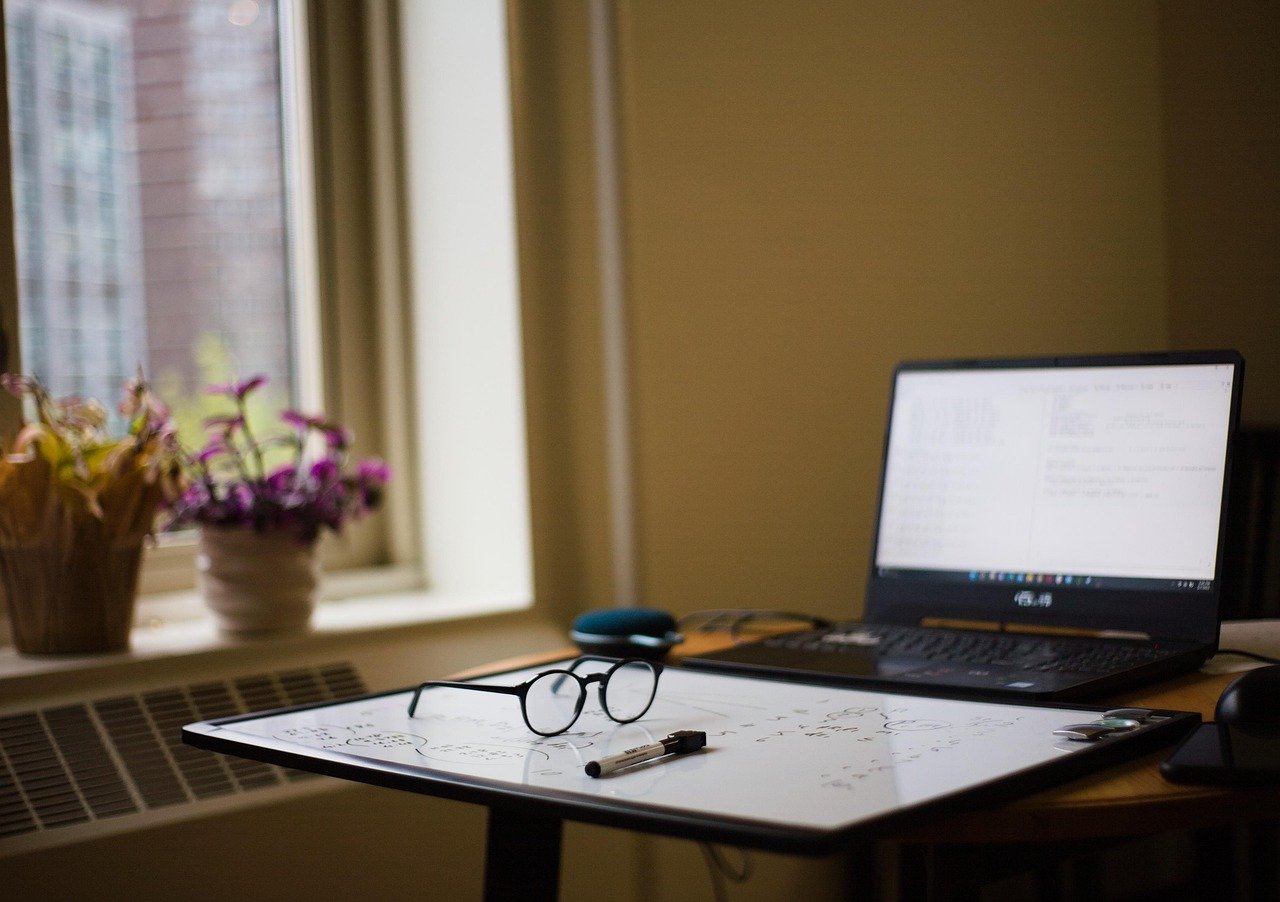 A desk set up for online studying, with a laptop and notes.