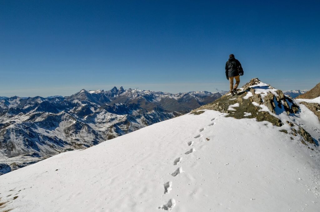 A hiker's-eye view of a snow-capped mountain summit under blue sky, symbolizing the long climb of personal growth and self-improvement.