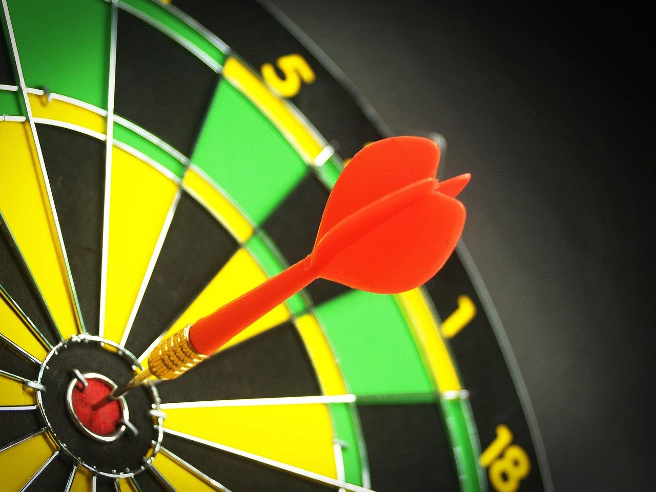 A dart hitting the bullseye of a dartboard, representing focused, specific goal-setting.
